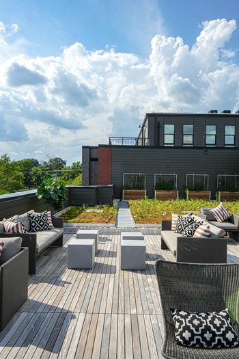 A modern outdoor seating area with a wooden deck and grey couches.